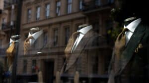 Four suit mannequins displayed with ties in a shop window