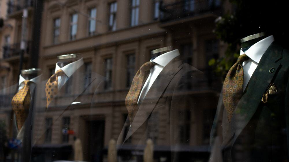 Four suit mannequins displayed with ties in a shop window