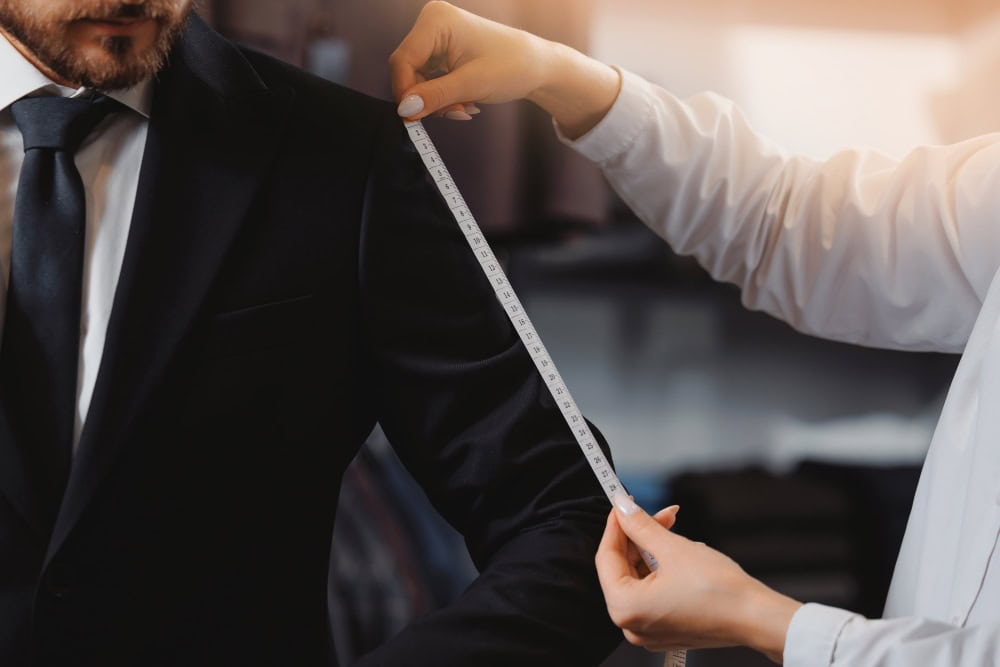 A tailor doing a suit fitting for a man