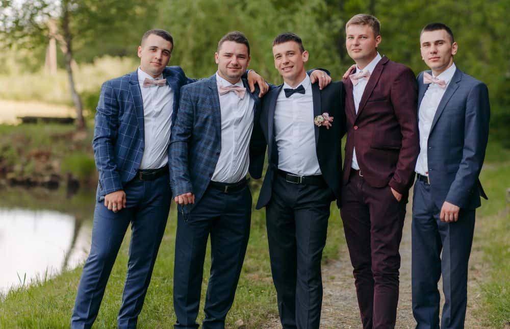 three men in suits and two with blazers and slacks pose for a photo