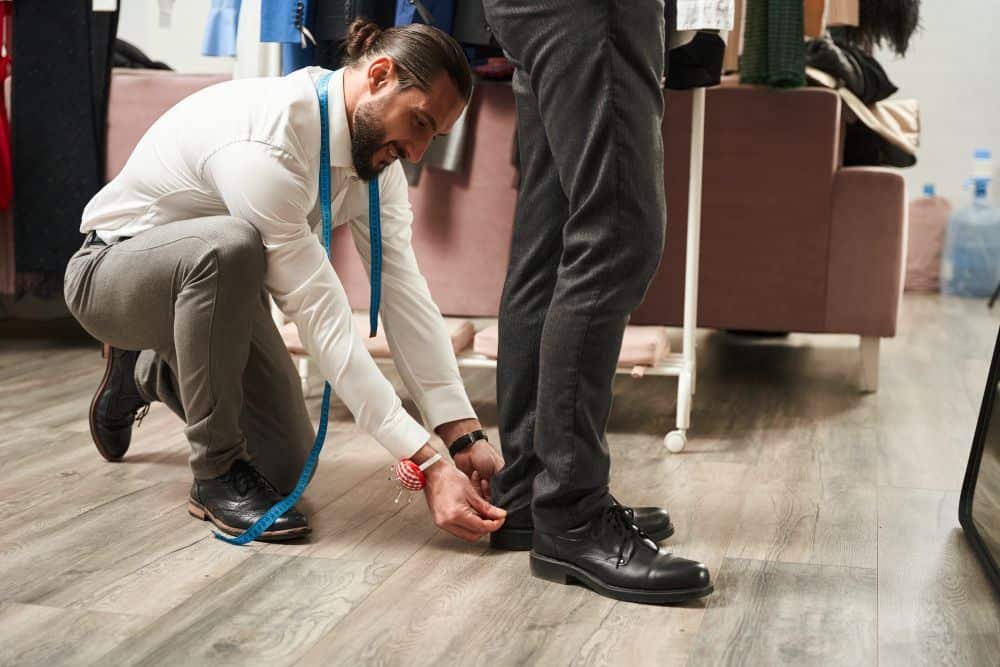 A tailor doing fittings for a customer’s pants