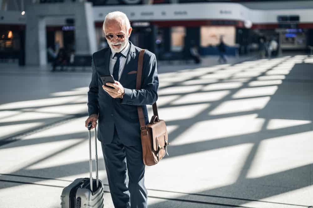 An elderly man in a sharp suit heading out from the airport