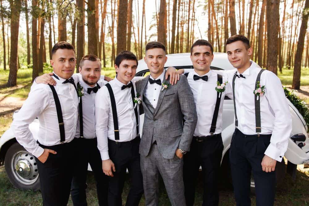 groom and his groomsmen showing off their suspenders
