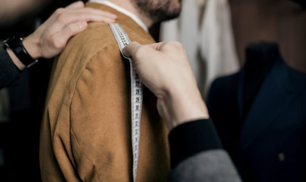 A tailor takes a man’s measurements to create a professional outfit suitable for men in Thailand.