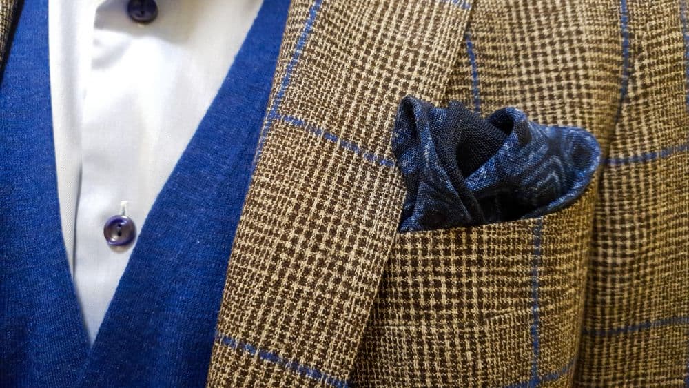 A navy wool suit hanging on a wide hanger, showing its wrinkle-free drape