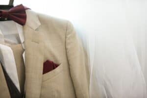 A light beige linen suit hanging on a rack, ideal fabric for hot weather