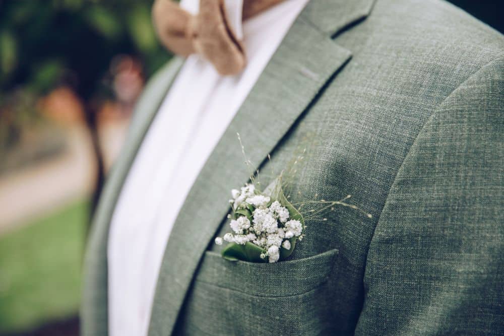 A groom wearing a linen suit at an outdoor wedding, showing the best suit for a hot weather
