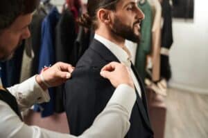 A tailor taking a client’s measurements during a fitting session as part of making suit alterations