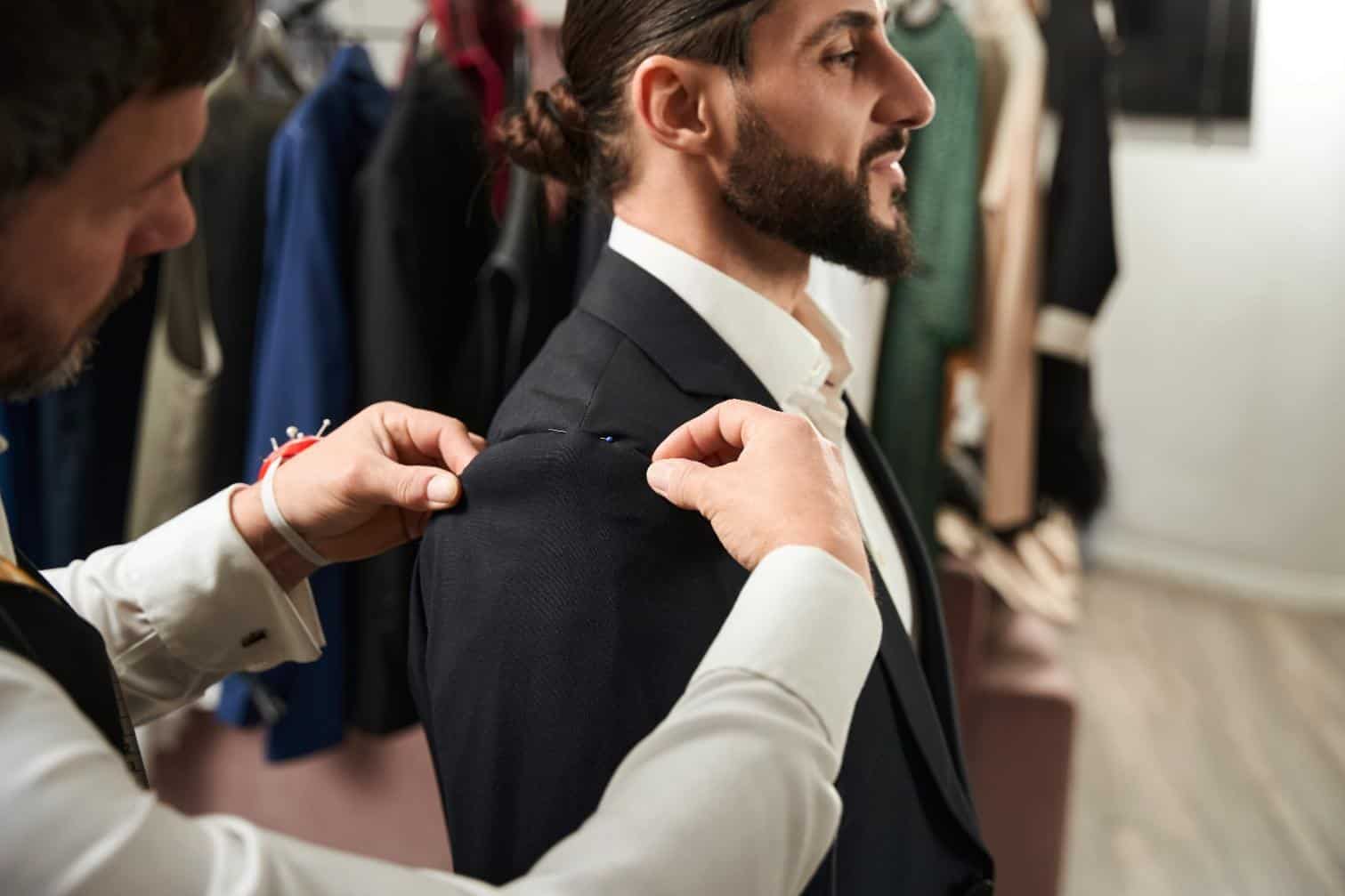 A tailor taking a client’s measurements during a fitting session as part of making suit alterations