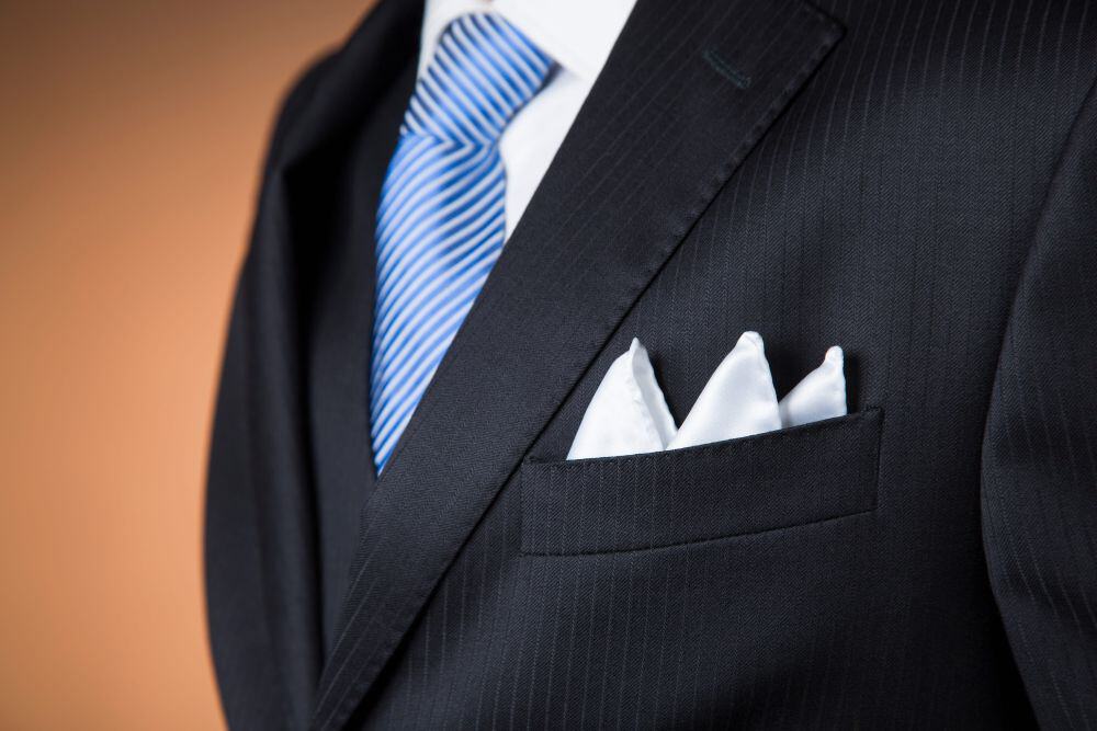 A tailor showing how to fold a pocket square on a suited mannequin