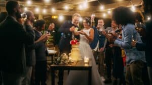 Men and women dressed in wedding guest outfits celebrating with drinks at an evening reception