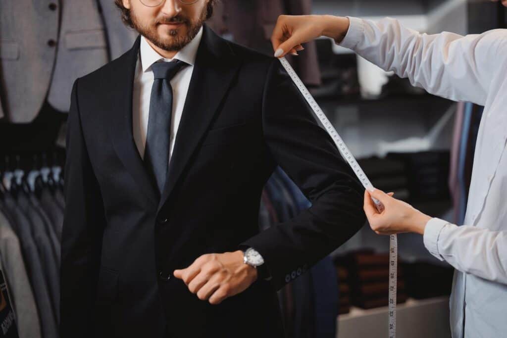 Tailor measuring a suit sleeve during a fitting appointment