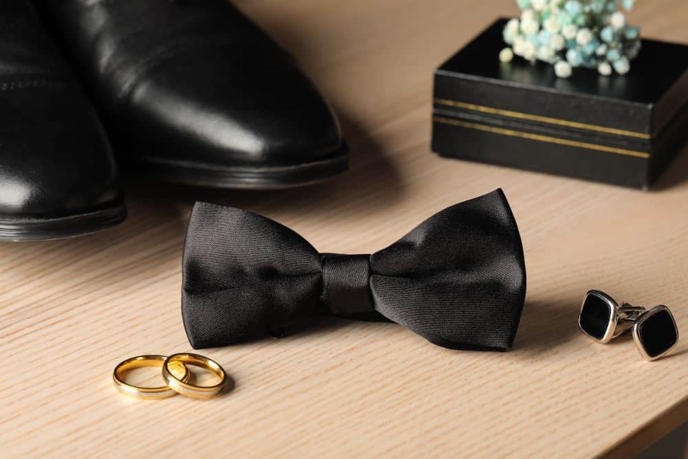 A black bow tie, polished formal shoes, and cufflinks. Important parts of black tie attire.